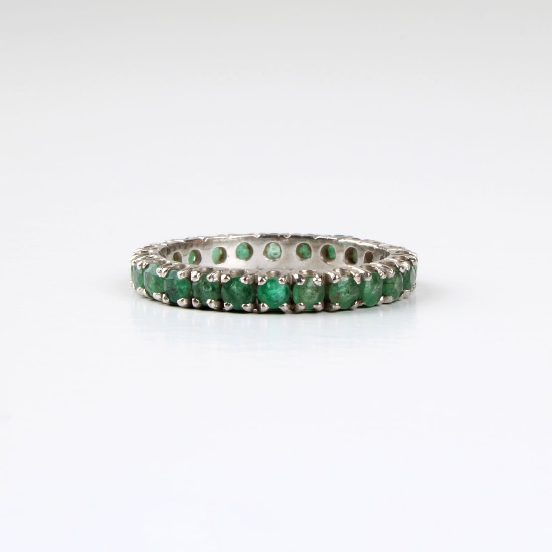 Emerald and 14K Band: Vintage Round Cut Emerald and 14 Karat White Gold Band / Ring. Ring size 7. Approx. weight: 1.96 grams. Kodner Galleries offers phone and absentee bidding at a low, flat 21% buyer’s premium without