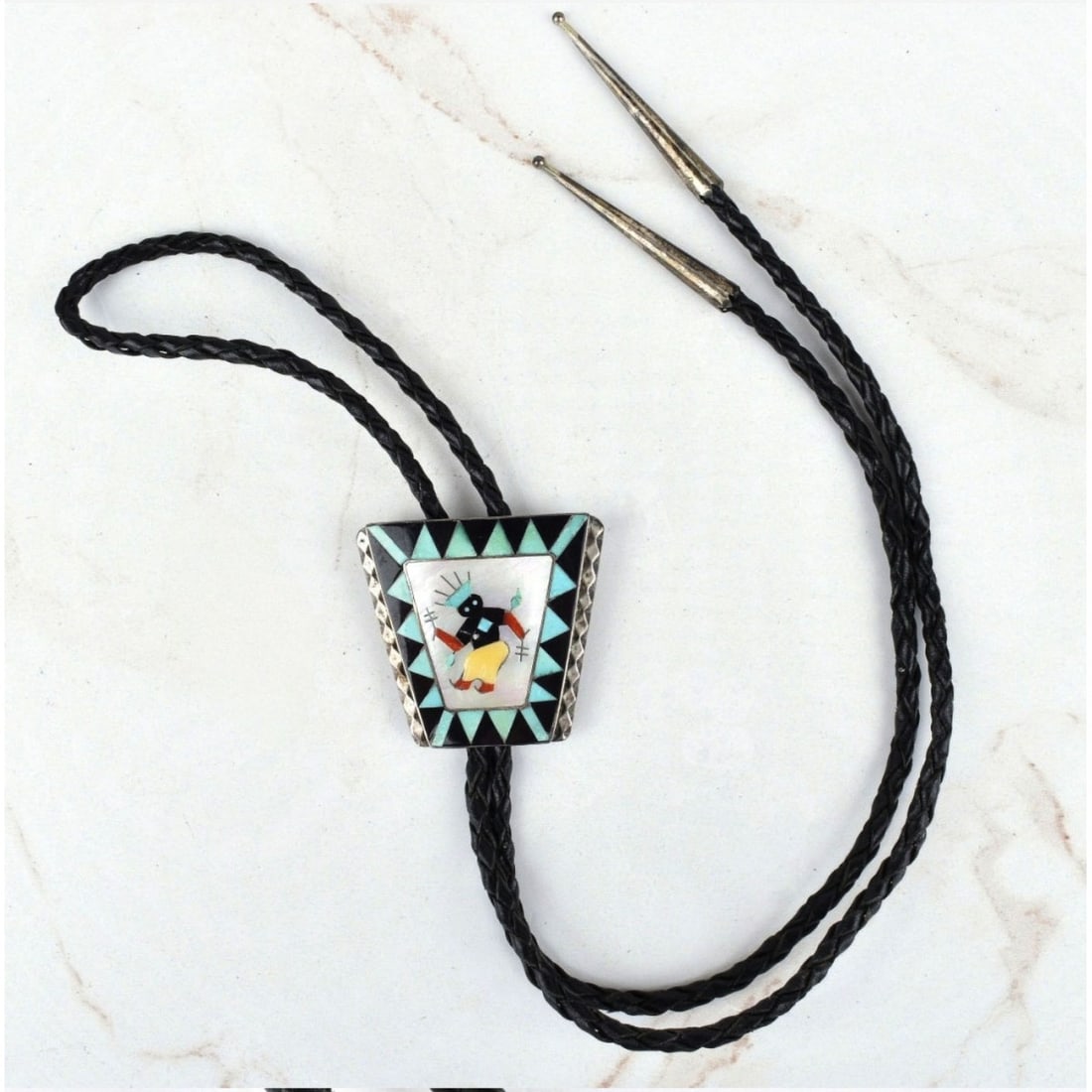 Native American Hardstone & Silver Bolo Tie: Vintage Native American Turquoise, Black Onyx, Mother of Pearl and Hardstone Inlaid Silver Bolo Tie with Braided Leather. Unsigned. Slider measures 1-7/8" H, 2" W; tie measures 38" L. Approx. gross