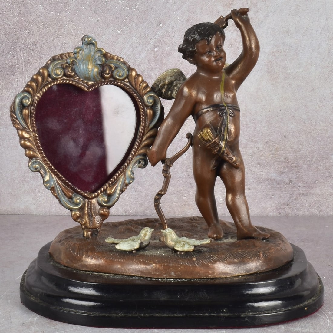Cupid Picture Frame: Bronze Toned Heart and Standing Cupid Picture Frame With Doves. Sculpture measures: 6-3/4" high, 7" wide, 4-1/2" deep. Kodner Galleries offers phone and absentee bidding at a low, flat 21% buyer’s