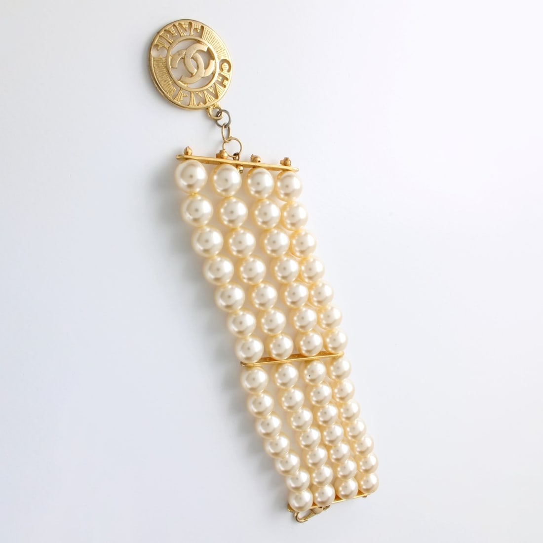Faux Pearl and Gold Tone Bracelet: Vintage Faux Pearl and Gold Tone Metal Wide Bracelet. Imitation Chanel tag. Measures 7-3/4" L, 2" W. Approx. weight: 67.69 grams. Condition: Good condition. Estimate: $50.00 - $150.00 In-House
