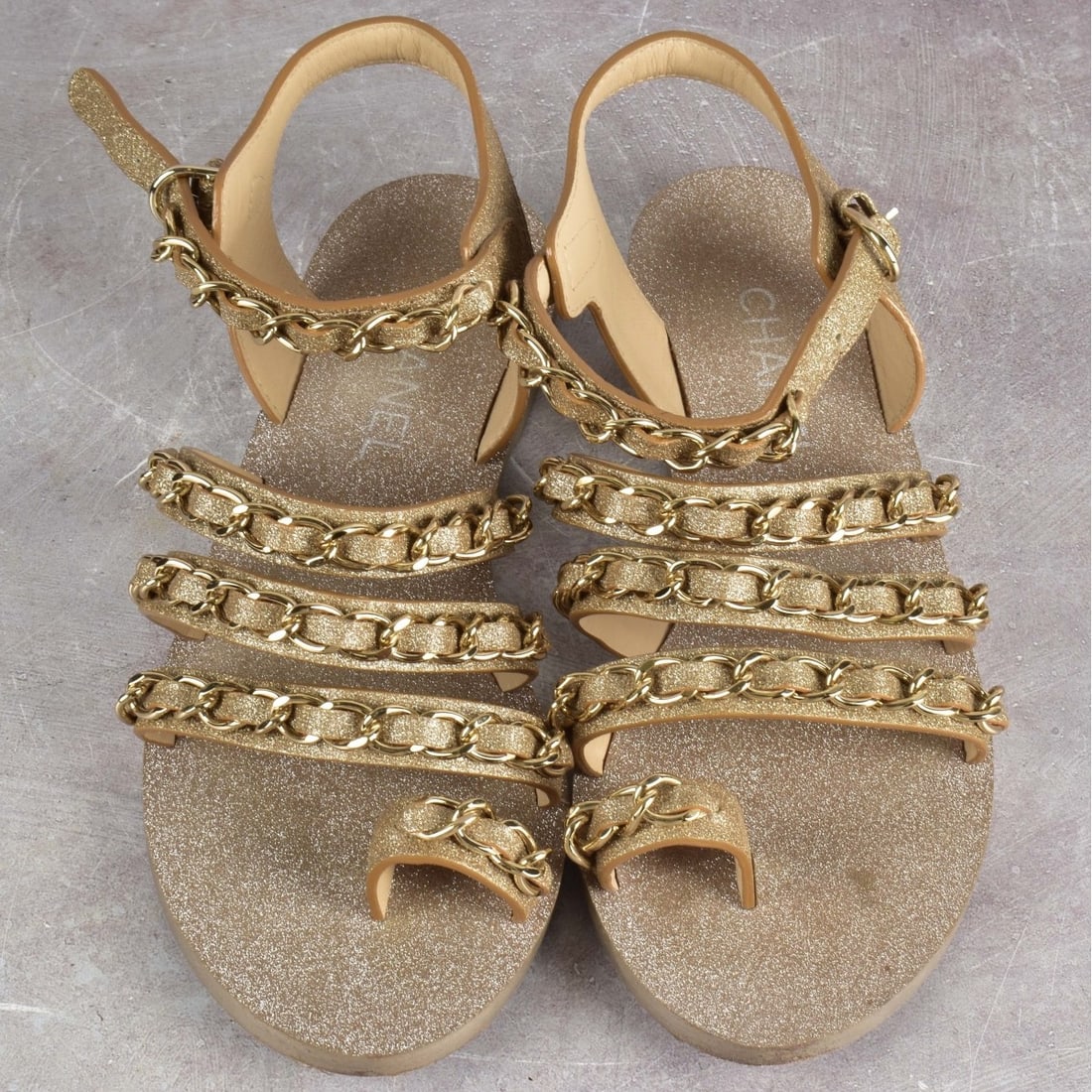 Chanel Leather Single Toe Sandals: Chanel Metallic Gold Leather Single Toe Sandals, with Strappy Chain Detail. Size Womens 38-1/2C. With box and tie ribbon. Provenance: The Orianne Collins Collection. Kodner Galleries offers phone and