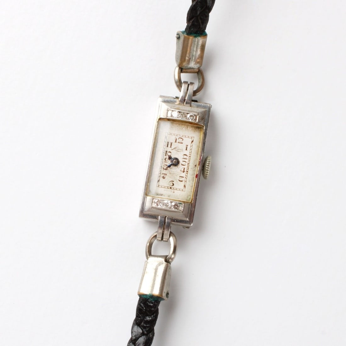 Art Deco Platinum Watch: Lady's Art Deco Louis Platinum Watch with Leather Bracelet. Accented with small round cut diamonds. Manual wind movement. Case measures 1-1/8" L, 3/8" W. Approx. gross weight: 10.22 grams. Kodner