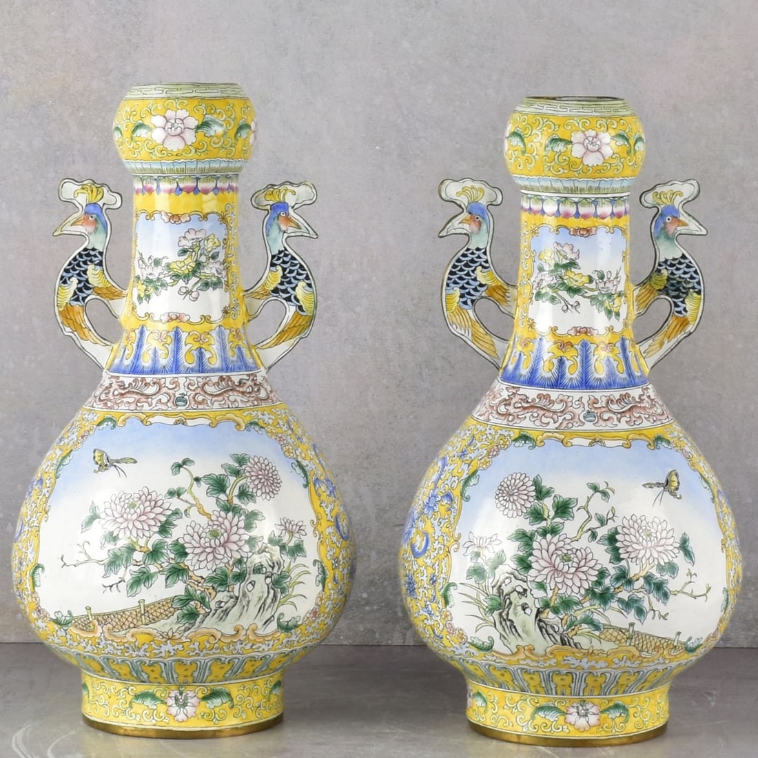 Vintage Chinese Enameled Vases: Vintage Chinese Garlic Bulbous Shape Painted Enamel on Metal Vases with a Floral Motif with Butterflies and Birds and Attached Peacock Handles. Measures: 15-1/4" high, 7-1/2" diameter. Kodner