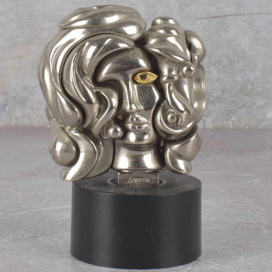 Miguel Berrocal 1933–2006 Mini Puzzle: Miguel Berrocal 1933–2006, " Portrait of Michele" (1969). Nickel plated puzzle sculpture with blue stone accented eye. Stamped ' berrocal" to base, numbered 7606 to verso. Black plastic plinth