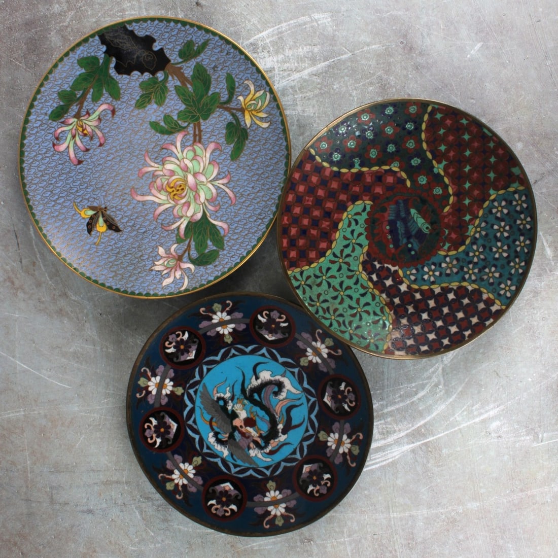 Japanese Bronze and Cloisonne Plates: Three (3) Japanese Meiji Period (1868-1912) Bronze and Cloisonne Display Plates Each Decorated with Stylized Flowers Flowers, the Reverse and Base in Bright Blue with Curled Wires. Largest measures: