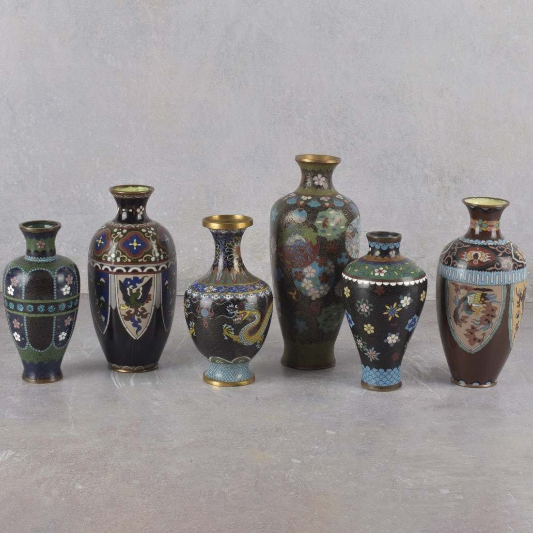 Japanese Cloisonne Vases: Six (6) Vintage Japanese Cloisonne Vases. Tallest measures: 9" high, 3-1/4" diameter, shortest measures: 6-1/8" high, 2-1/2" diameter. Kodner Galleries offers phone and absentee bidding at a low, flat