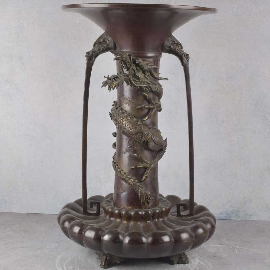 Massive Japanese Antique Bronze Urn: Massive Sculptural Japanese Antique Bronze Urn, Circa 1880. Decorated with a large dragon entwined around and two long arc arms tapering down and up to a wide flaring mouth and a segmented base suppor