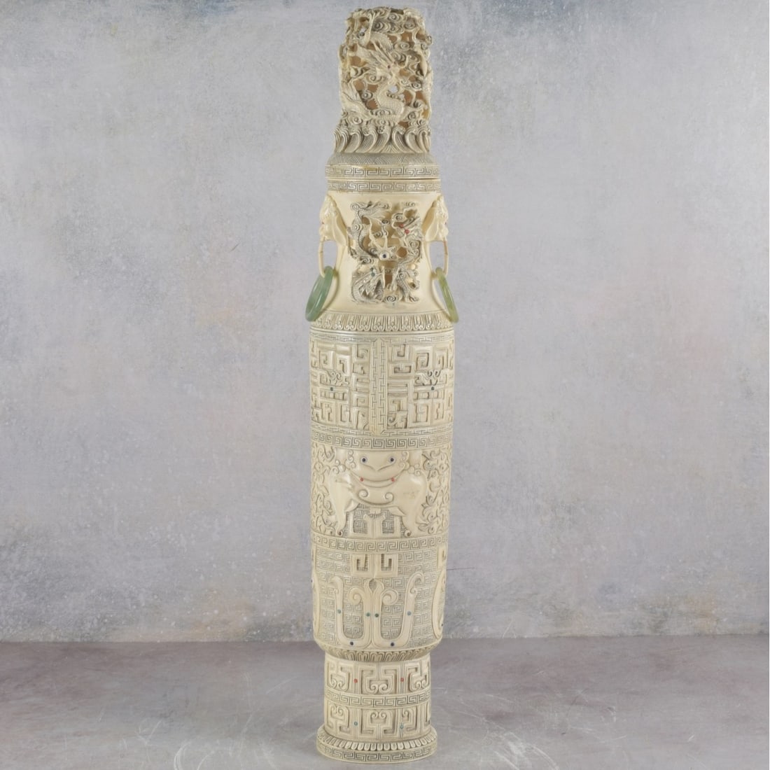 Carved Chinese Covered Vase: Finely Carved Chinese Covered Vase with Replaced Jade Handles and Various Inlaid Stones. Late 19th century. Rouleau form with well carved dragons in search of sacred jewels. Artist signed to base of v