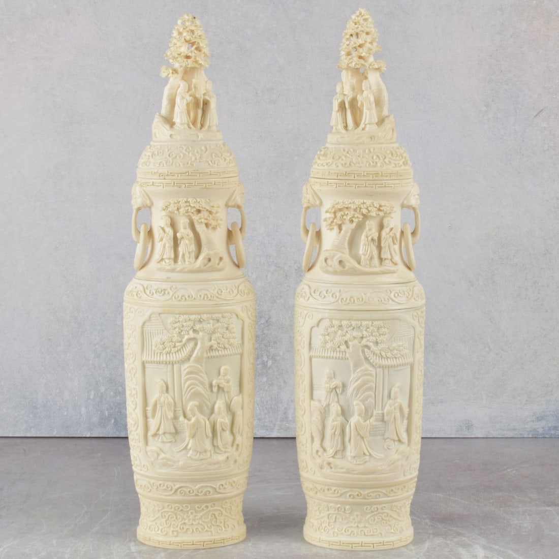 Vintage Caved Pair of Chinese Urns: Vintage Carved Organic Material Organic Material Pair of Chinese Lidded Urns with Attached Ring Handles. Decorated with carved Pagodas and Figures Under Lotus Trees. We Will Not Ship This Item Outside