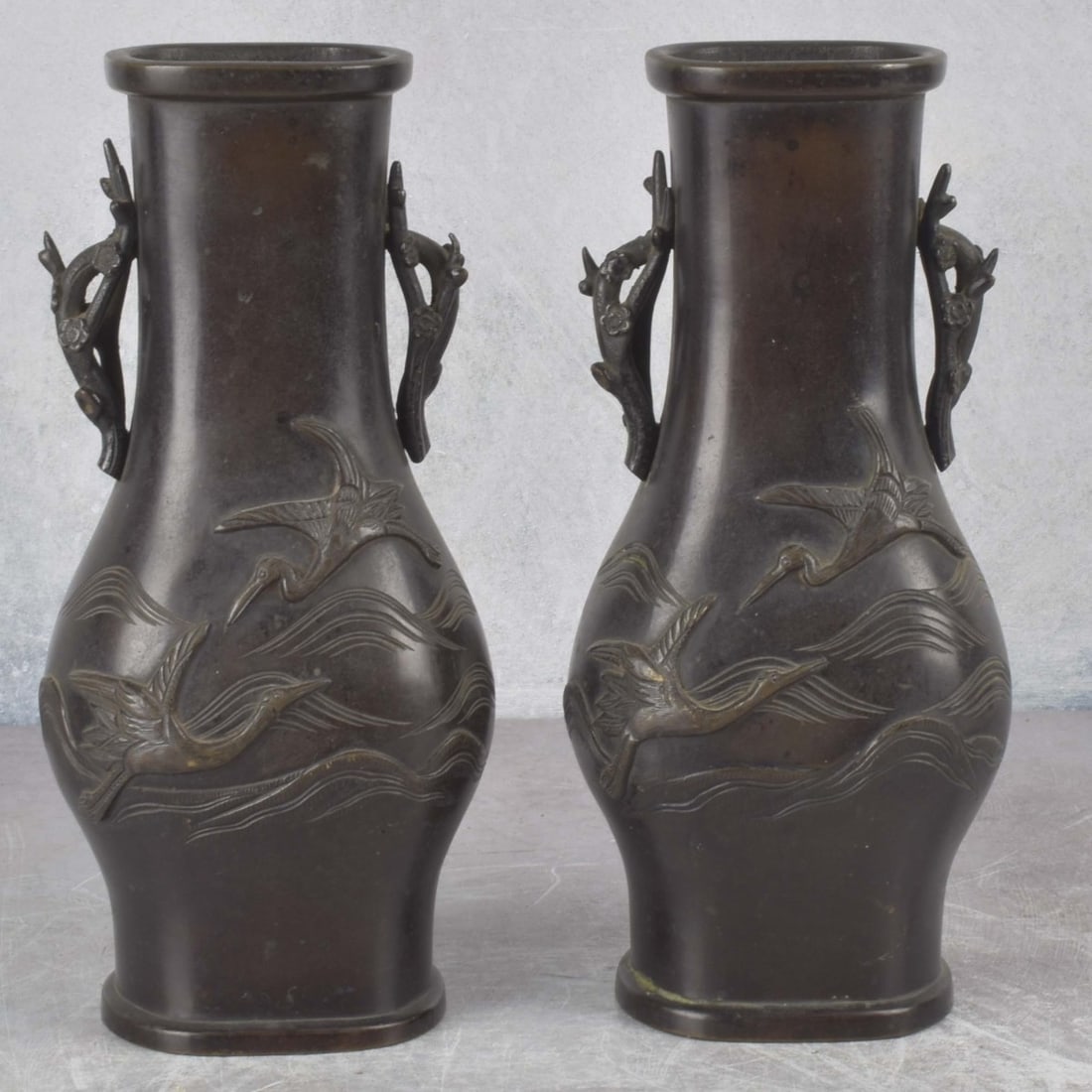 Antique Japanese Bronze Vases: Antique Japanese Bronze High Relief Vases with Cranes over Water with Attached Handles in the Form of Branches with Flowers. Meiji period (1868-1912). Measures: 9-1/2" high, 4" wide, 3" deep. Kodner G