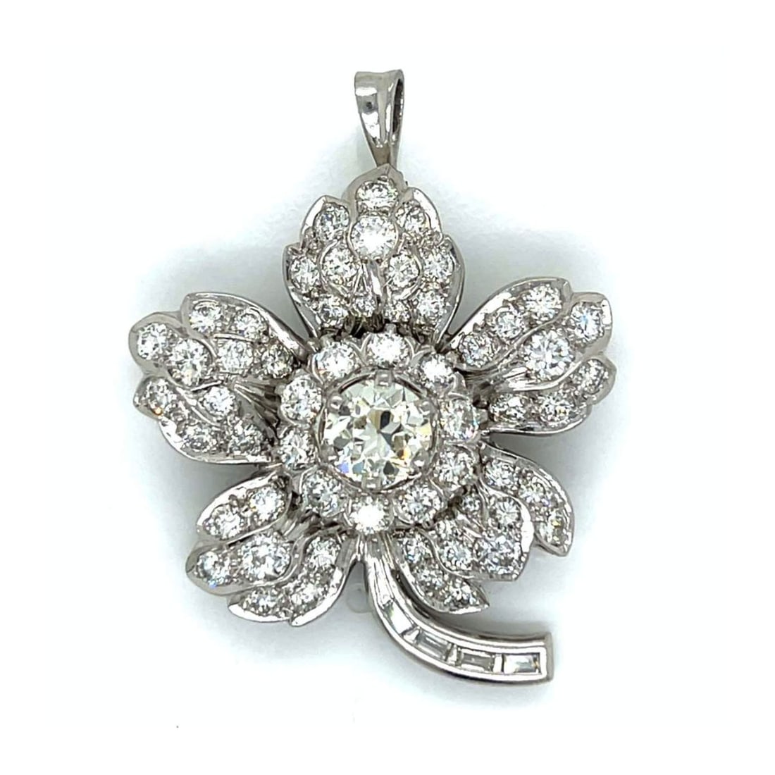 Diamond and Platinum Pendant / Brooch: Vintage Circa 1960s Art Deco style Diamond and Platinum Flower Pendant / Brooch. Set in the center with an approx. 1.85 carat round brilliant cut diamond, L color, VVS clarity and accented with approx