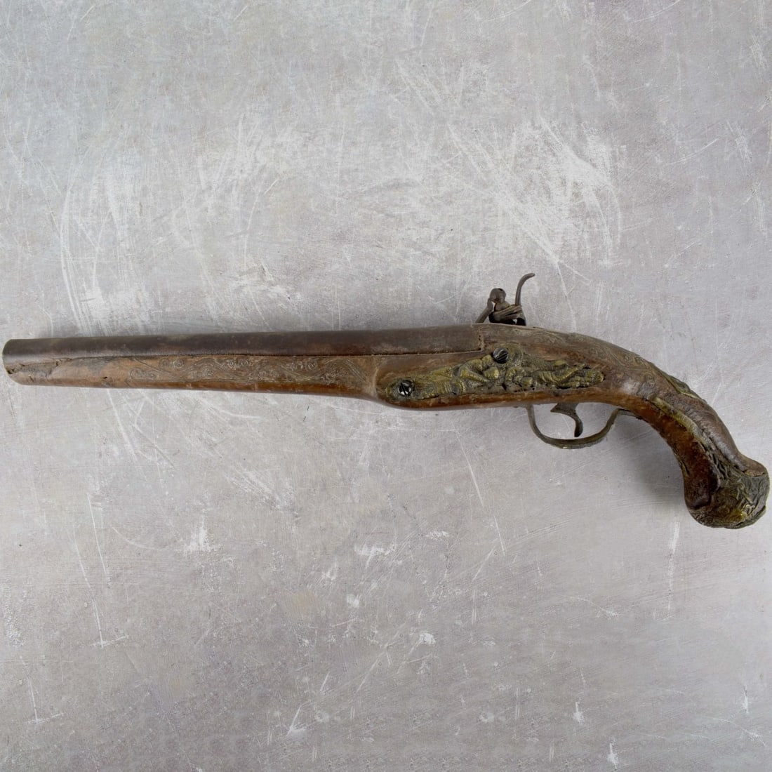 Flintlock Pistol: Antique 18/19th Century Flintlock Pistol. Carved walnut stock with engraved steel mounts. Measures 18" L. Condition: Antique used condition. Small wood losses. Some newer elements. Estimate: $200.00 -