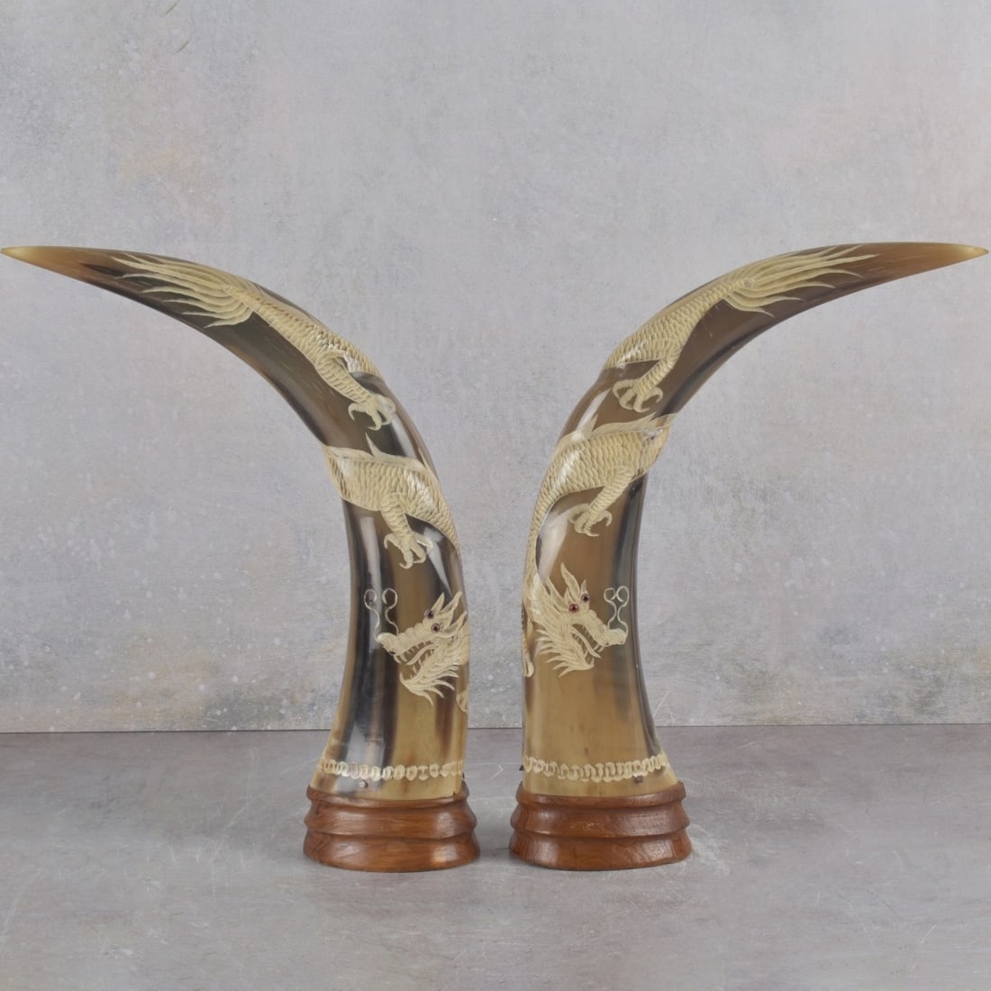 Vintage Carved Buffalo Horns: Pair of Vintage Carved Buffalo Horns with Carved Dragons having Red Stone Eyes. Measures: 12-1/2" high. Kodner Galleries offers phone and absentee bidding at a low, flat 21% buyer’s premium without