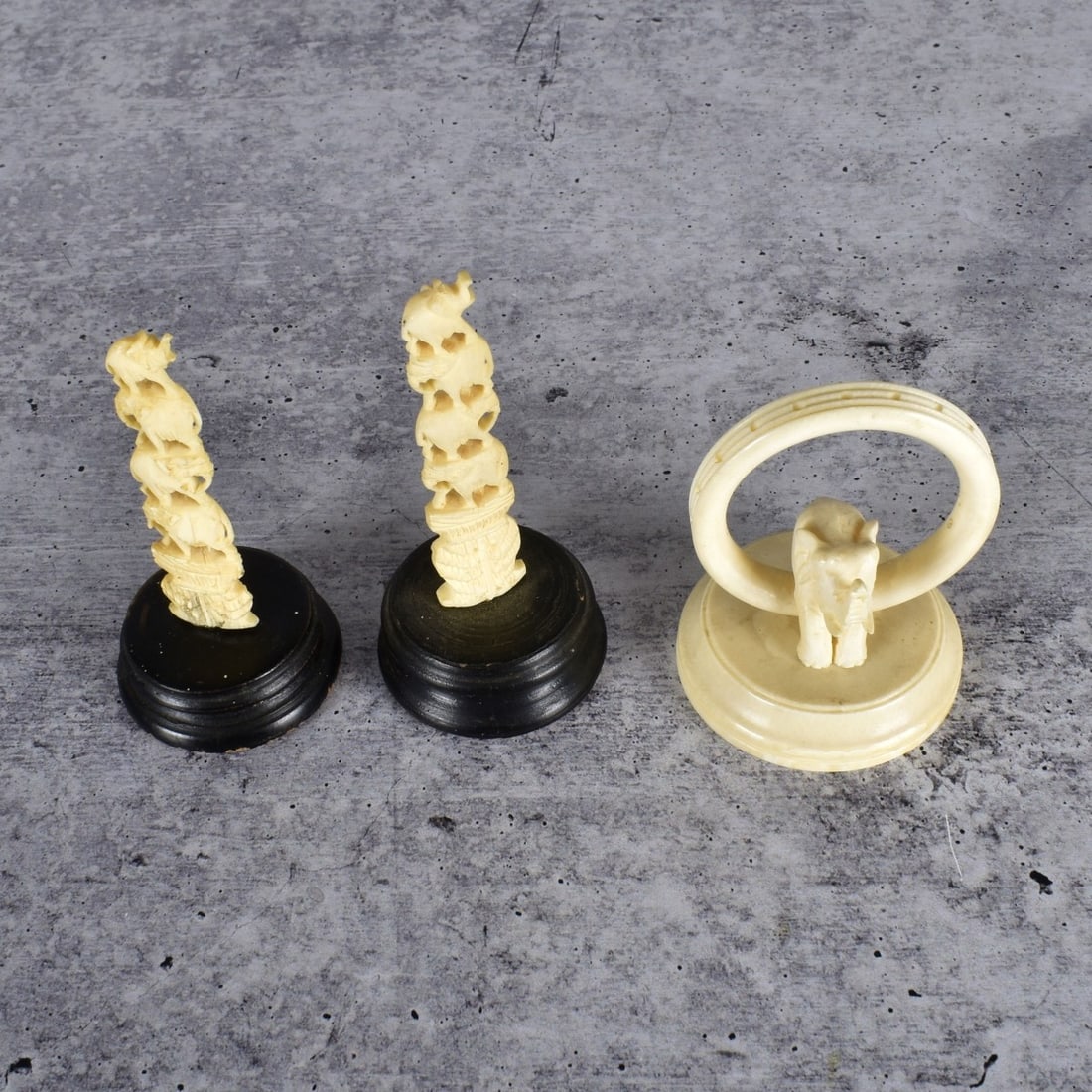 Three African Carved Miniature Figurines: Lot of Three African Carved Miniature Figurines. Lot includes a pair of stacked elephants along with a single elephant with handle. Pair of figurines measure 3-1/2" H. Remaining figurine measures 2-1/