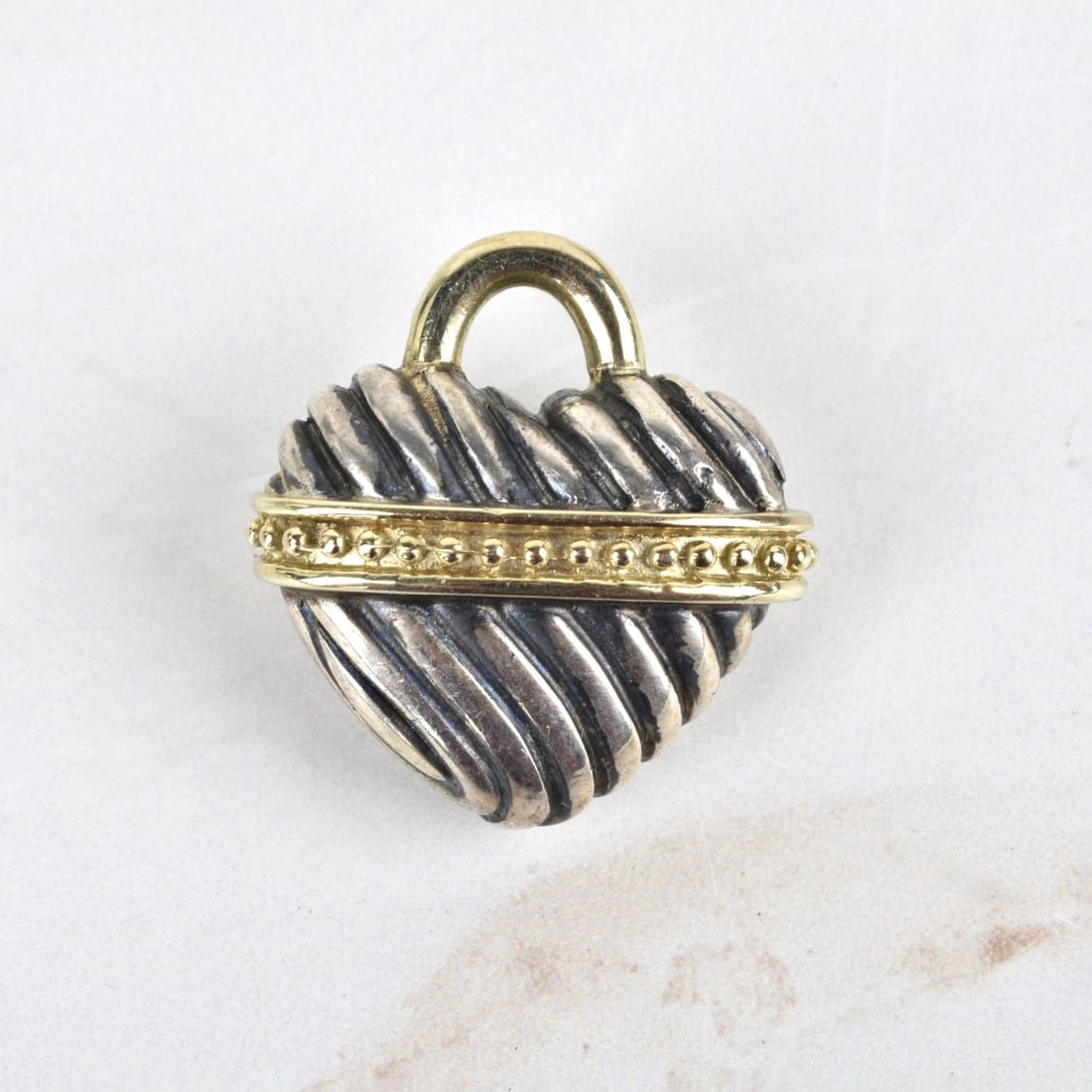 14K and Sterling Heart Pendant: Vintage 14 Karat Yellow Gold and Sterling Silver Heart Pendant. Stamped 14K SS BK. Measures 1-1/8" H, 1-1/16" W. Approx. weight: 18.33 grams. Kodner Galleries offers phone and absentee bidding at a lo