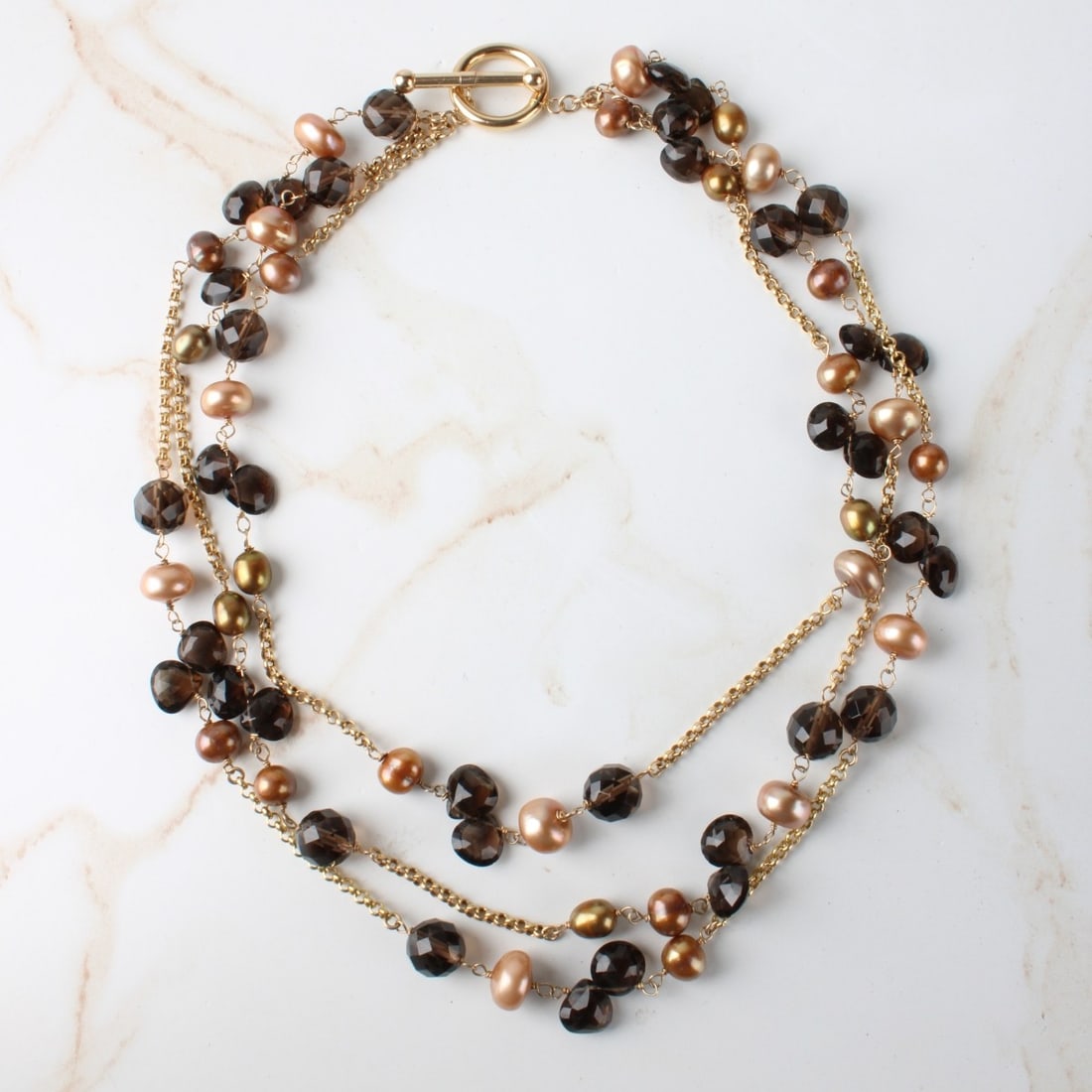 Quartz, Pearl and 14K Necklace: Vintage Three Strand Faceted Smokey Quartz Bead, Golden Pearl and 14 Karat Yellow Gold Necklace. Measures 17" L. Approx. weight: 61.83 grams. Kodner Galleries offers phone and absentee bidding at a lo