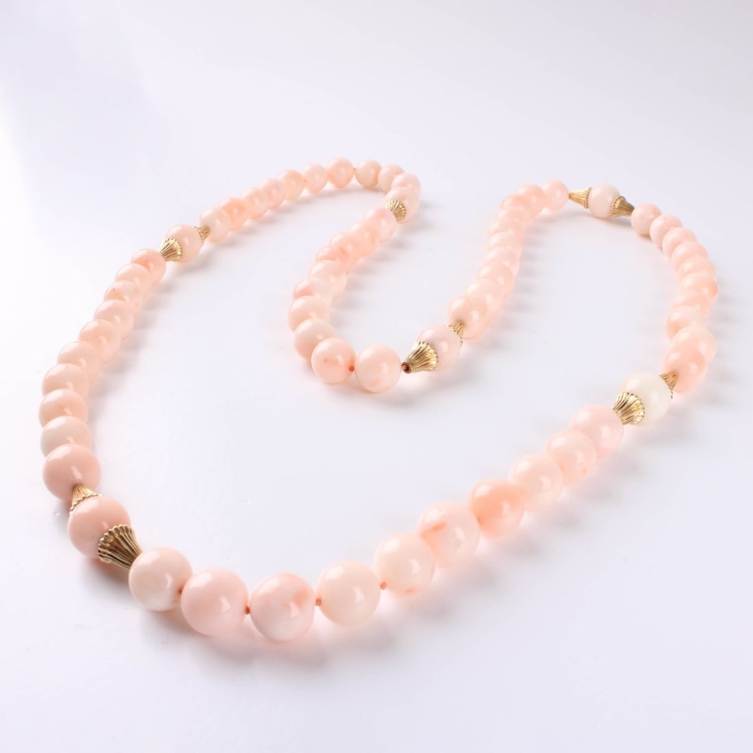 Coral and 14K Necklace: Vintage 10mm Angle Skin Coral Necklace with 14 Karat Yellow Gold Spacers. Measures 30" L. Approx. weight: 96.34 grams. Kodner Galleries offers phone and absentee bidding at a low, flat 21% buyer’s