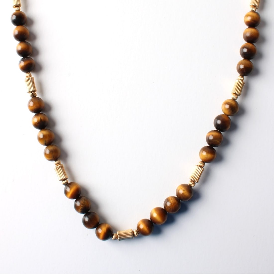 Tiger Eye and 14K Necklace: Vintage 10mm Tiger Eye Bead and 14 Karat Yellow Gold Necklace. Clasp stamped 14K. Measures 26-1/4" L. Approx. weight: 71.78 grams. Kodner Galleries offers phone and absentee bidding at a low, flat
