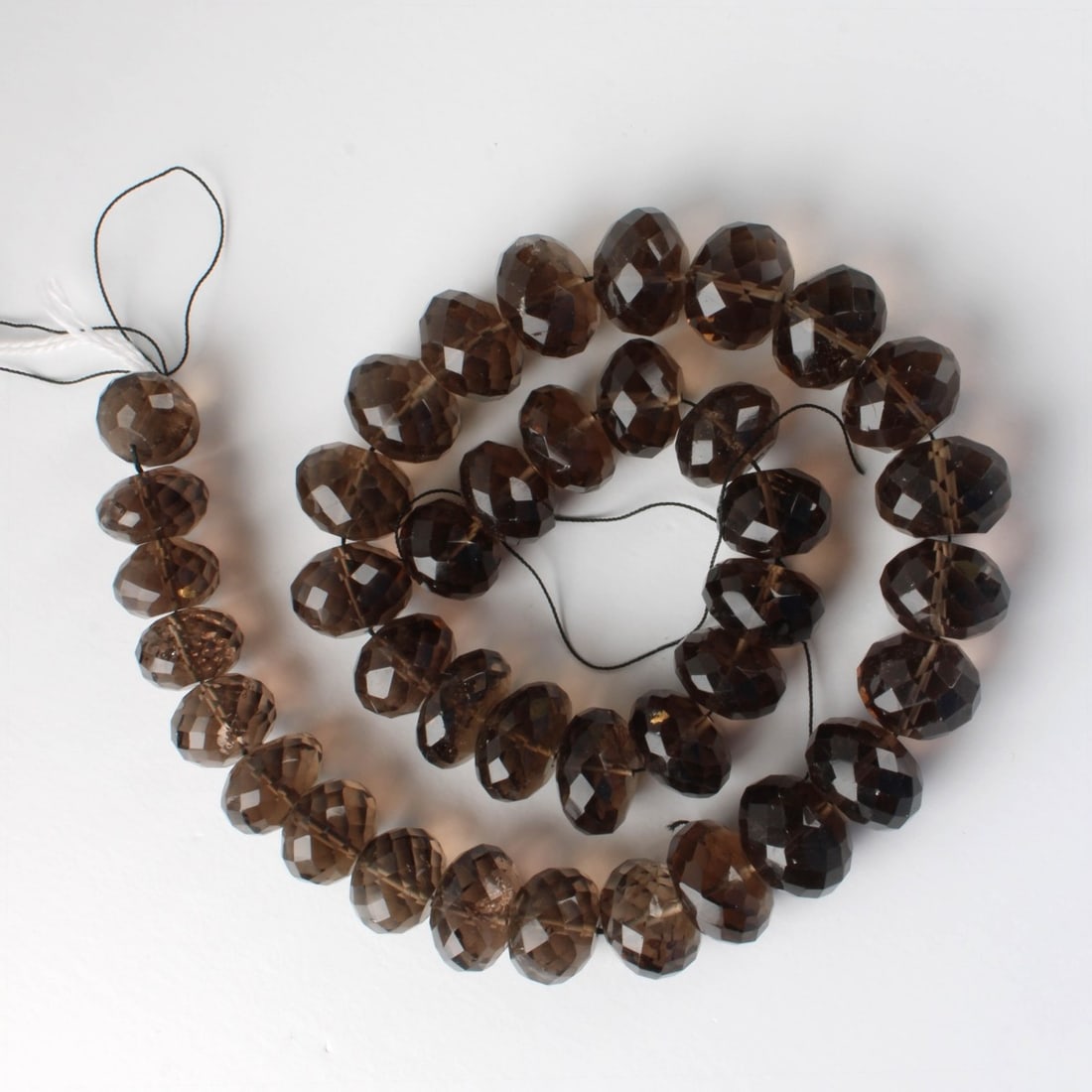Smokey Quartz Beads: Vintage Single Strand of 932 Carats TW 39 Graduated Faceted Smokey Quartz Beads. Range from 15-18mm. Approx. total weight: 186.21 grams. Kodner Galleries offers phone and absentee bidding at a low, fl