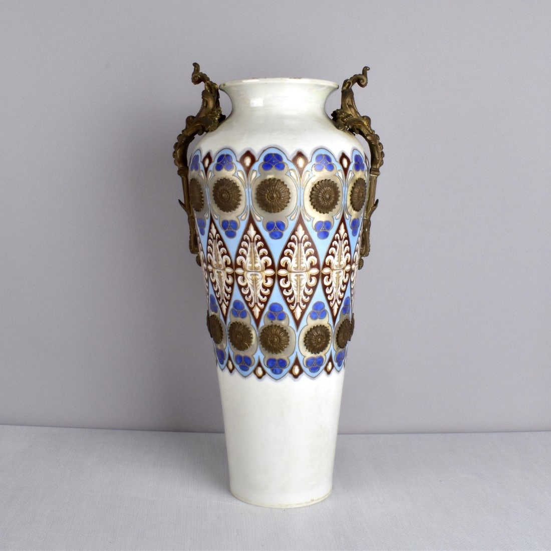 French Art Nouveau Vase: Antique 19C/20C French Art Nouveau Bronze Mounted Porcelain Vase. Iridescent white porcelain ground with blues and brown geometric patterns accented with gold. Interspersed with small bronze medallion