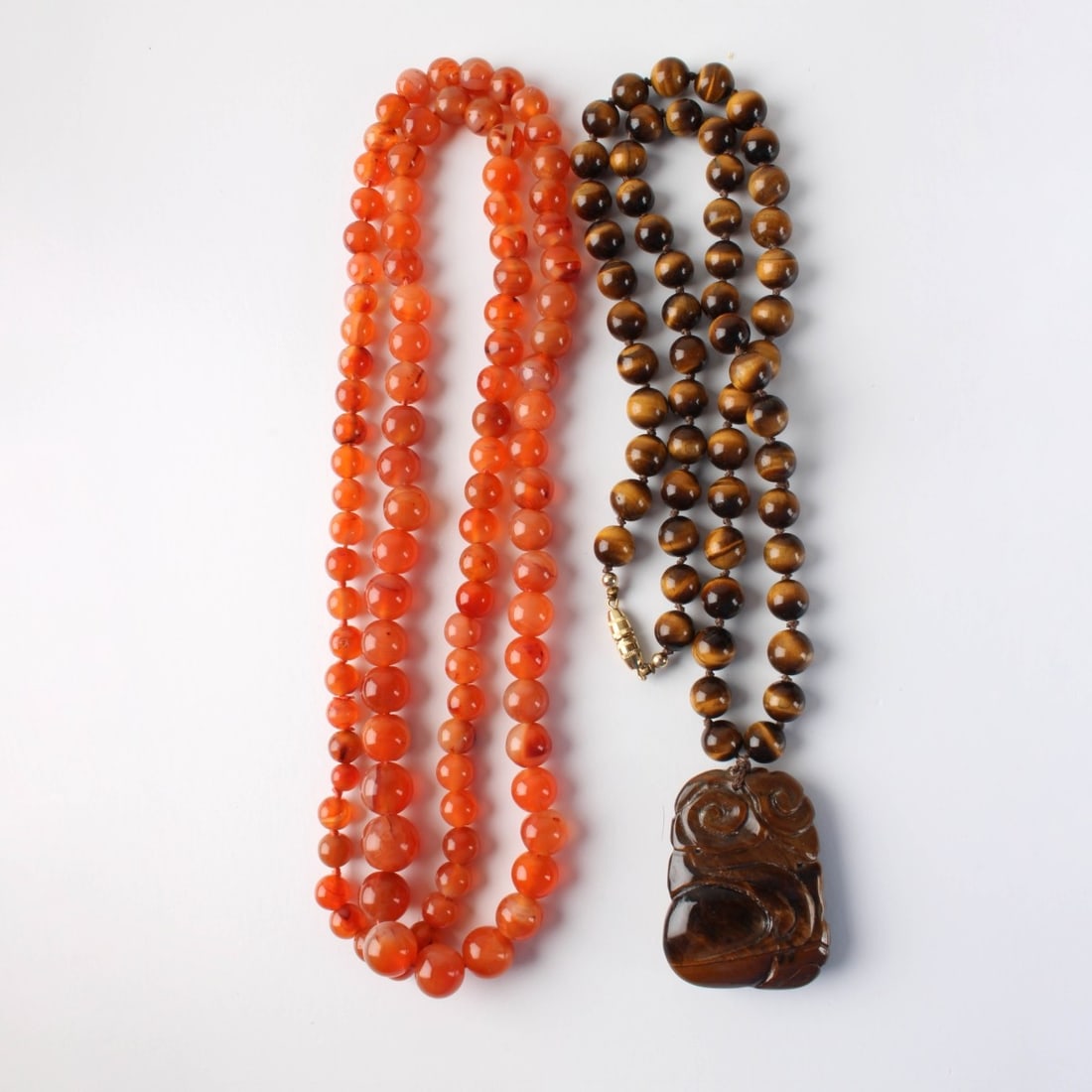 Hardstone Necklaces: Two Vintage Hardstone Necklaces. Consisting on one (1) tiger eye pendant necklace, measures: 26" long, pendant measures: 1-7/8" long, weighs: 113.1 grams, one (1) carnelian bead necklace, measures: 19