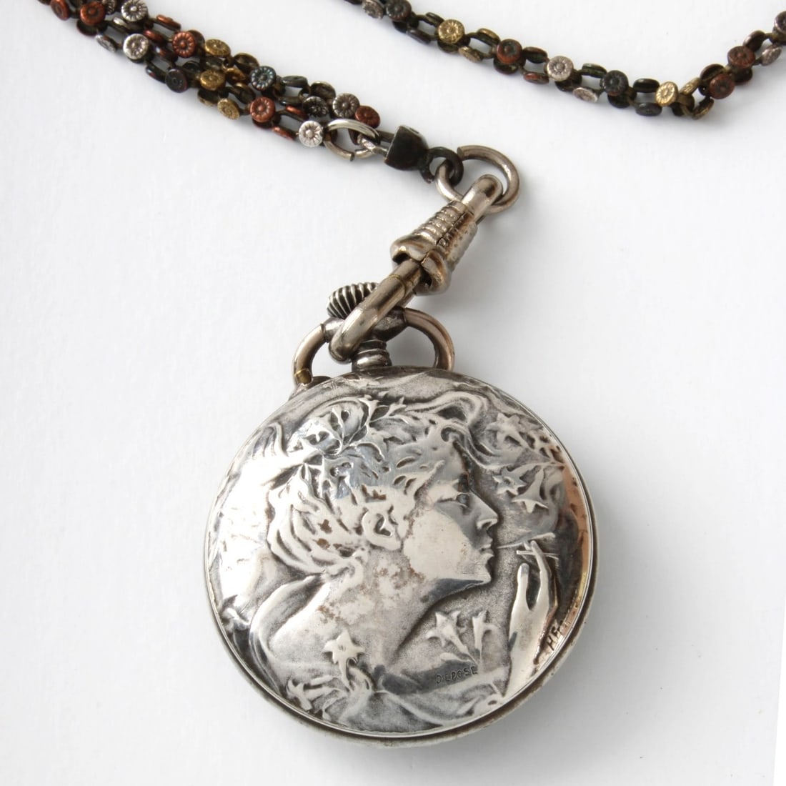 Art Nouveau Pocket Watch and Chain: Lady's Antique French Art Nouveau Silver Pendant Pocket Watch on Long Tro Color Mixed Metal Chain. Manual wind movement. White porcelain dial. Case measures 29mm; chain measures 44" L. Case back with 