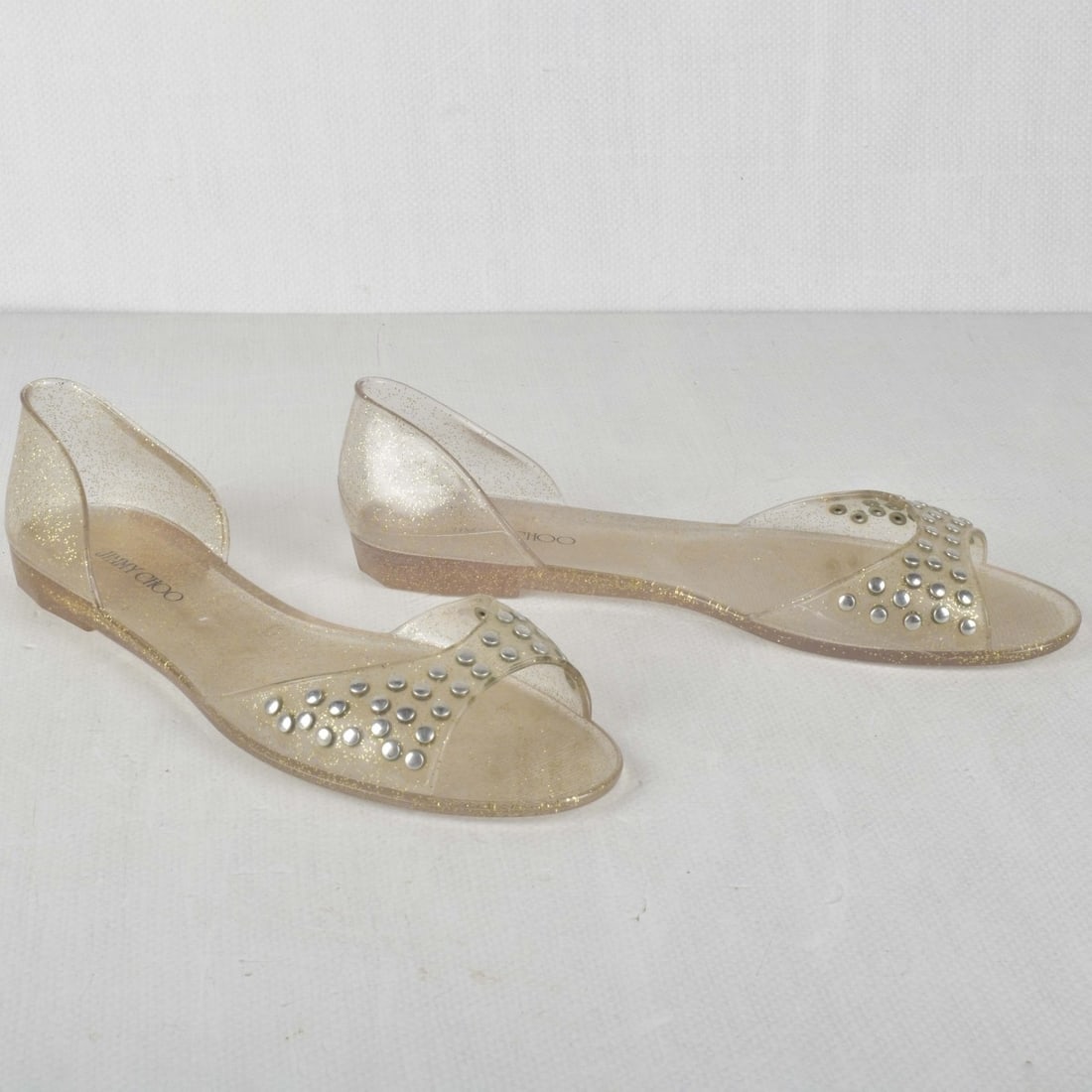 Jimmy Choo JILL Flats: Jimmy Choo JILL Flats with Gold Glitter Studded Clear PVC Jelly Shoes. Size: Eu 40. Kodner Galleries offers phone and absentee bidding at a low, flat 21% buyer’s premium without surcharge or hidden