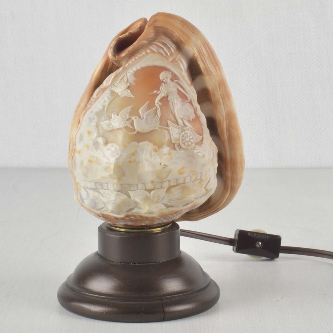 Vintage Carved Conch Shell Night Light: Vintage Carved Conch Shell Night Light with a Carved High Relief Roman Woman Standing in a Chariot with Flying Doves and Garlands and a Lower Boarder of Flowers Mounted to a Turned Wood Base. Shell me