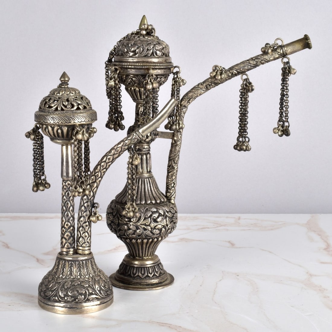 Grouping of Middle Eastern Hookah Pipes: Grouping of Two Antique Middle Eastern Repousse Silver Hookah Pipes with Hanging Tassels. One is marked "Silver" on the base. Tallest measures: 8-1/2" H, 2-1/4" W, 6-1/2" D. Remaining pipe measures