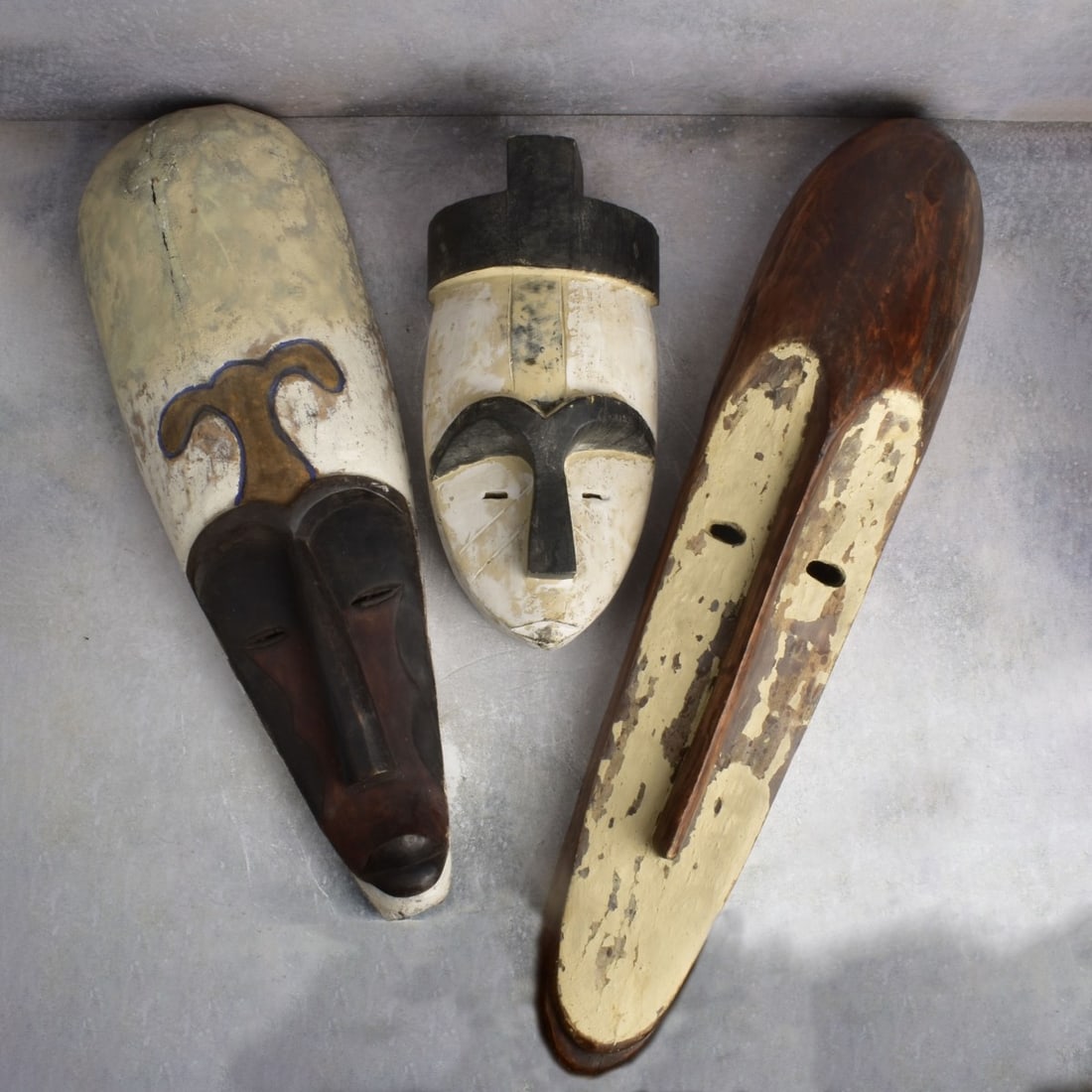 African Carved Wood Masks: Three (3) African Carved Wood and Painted Masks from the Fang Tribe of Gabon. Largest measures: 37" H., 7" W., 6" D., smallest measures: 17" H., 8" W., 6" D. Kodner Galleries offers phone and absentee