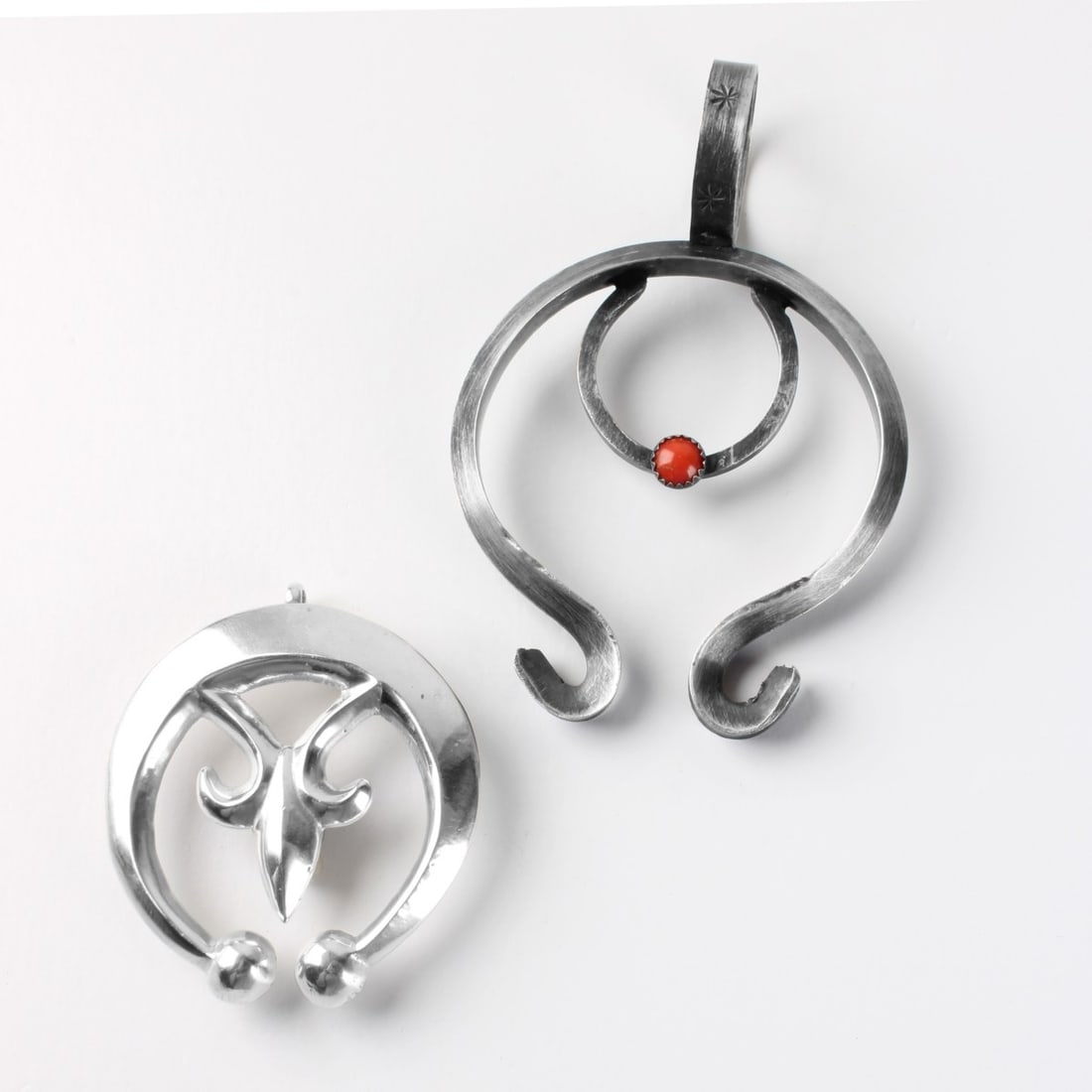 Sterling Silver Pendants: Two Vintage Sterling Silver Pendants, One with a small Red Coral Accent. Both stamped sterling. Largest measures 3-1/2" L, 2-3/8" W. Approx. total weight: 74.25 grams. Kodner Galleries offers phone