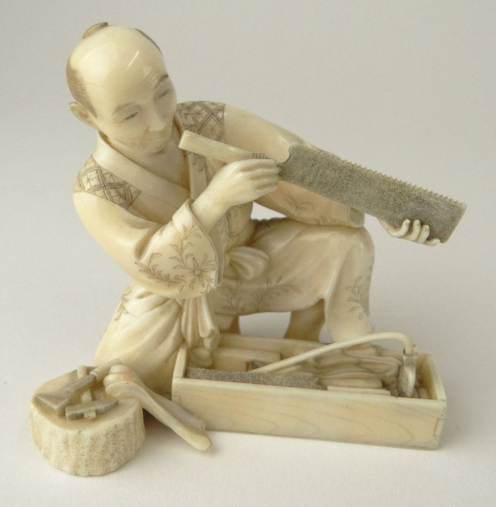 Finely Carved 19th Century Japanese Ivory Netsuke: Finely Carved 19th Century Japanese Ivory Netsuke "Carpenter Examining a Saw" Signed on Red Cartouche Under Base. Very Good Condition. Measures 2-5/8 Inches Tall and 2-3/4 Inches Wide. This item will 