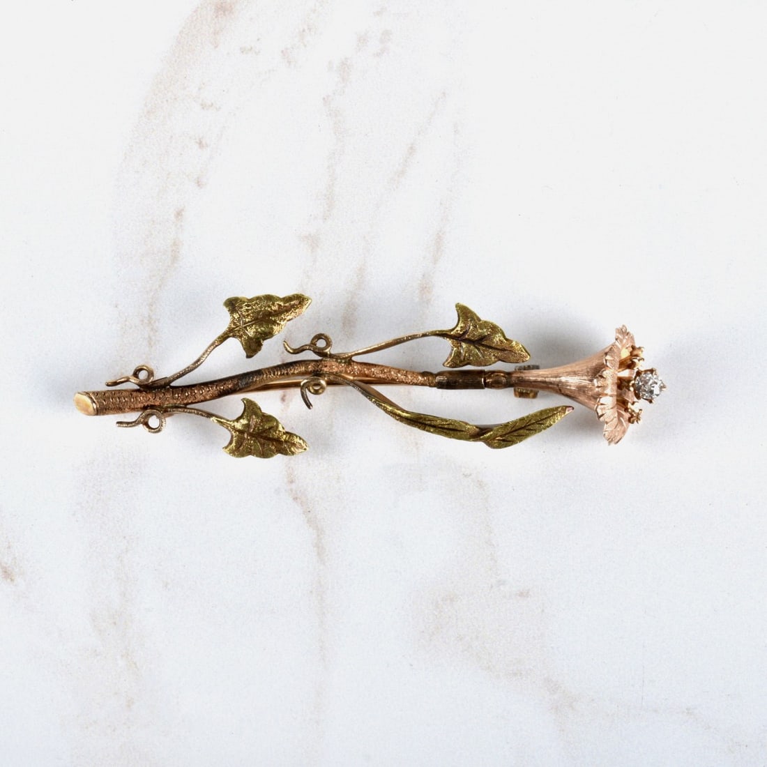 Diamond and 14K Brooch: Antique 19th Century Victorian Approx. .20 Carat Old European Cut Diamond and 14 Karat Pink and Yellow Gold Flower Brooch. Diamond H color, SI1 clarity. Measures 2-5/8" L, 5/8" W. Approx. weight: 9.43