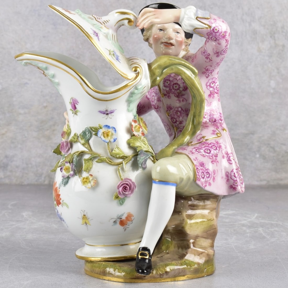 Meissen German Porcelain Ewer: Late 19th-early 20th Century Meissen German Porcelain Figural Ewer. In the form of a man on a tree stump besides an encrusted ewer with gold gilding. Marked with the Meissen cross swords under glaze a