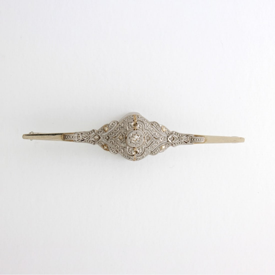 Diamond and 14K Bar Pin: Antique Victorian Filigree 14 Karat White Gold Bar Pin Accented with Small Round and Rose Cut Diamonds. Measures 2-1/2" L, 1/2" W. Approx. weight: 4.61 grams. Kodner Galleries offers phone and