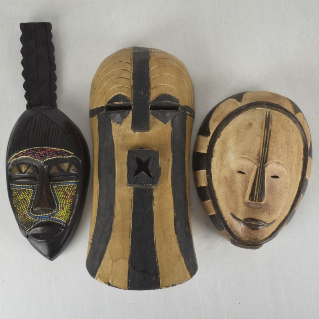 Carved Tribal Masks: Three (3) Hand Carved Wood and Painted Tribal Masks. Tallest with beads measures: 17-3/4" long, 6-1/8" wide, 3-1/4" deep. Kodner Galleries offers phone and absentee bidding at a low, flat 21% buyer?s
