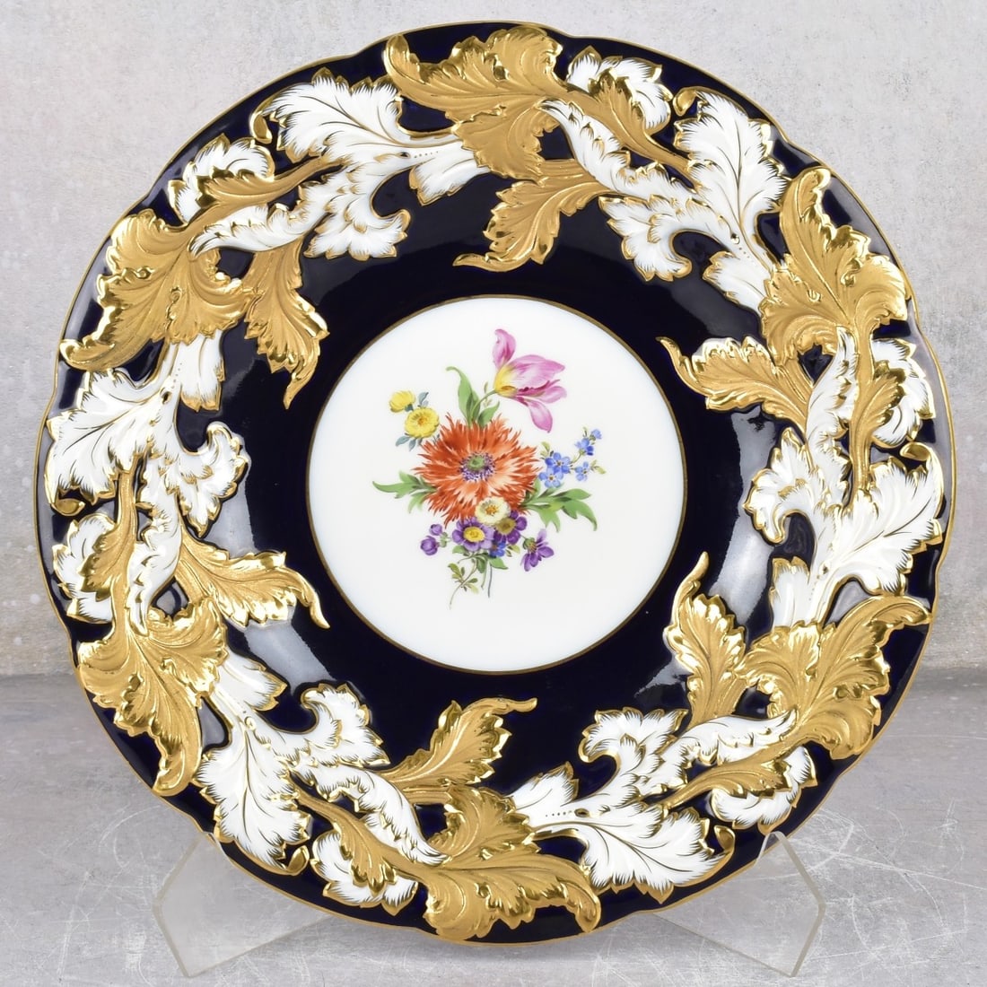 Meissen Porcelain Shallow Bowl: Meissen Porcelain Shallow Bowl With Heavy Gold Decoration with a Central Medallion of Painted Flowers and Raised Foliage Edge. Marked with the Meissen crossed swords under glaze and incised numbers. M