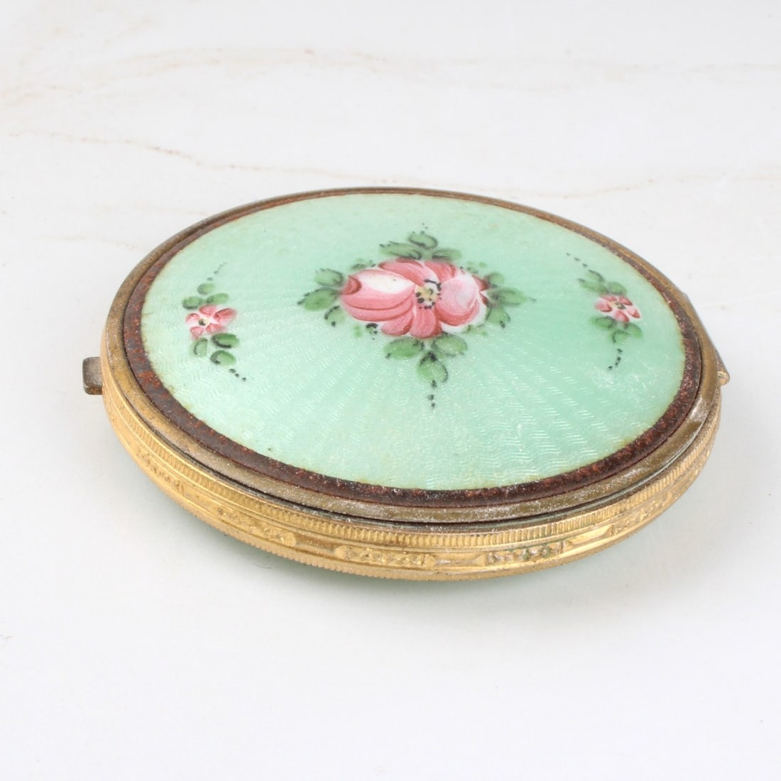 Green Guilloche Enamel Powder Box: Vintage Green Guilloche Enamel Powder Box with Hand Painted Rose Motifs and a Gold Tone Metal Hinge. Measures: 2-1/4" diameter. Kodner Galleries offers phone and absentee bidding at a low, flat 21%
