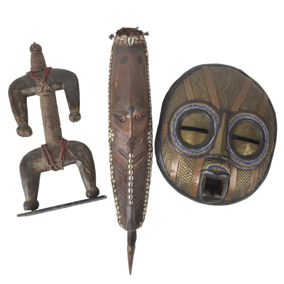 Vintage African Tribal Art Wood Sculptures: Four (4) Vintage African Tribal Art Wood Sculptures. One mask with attached cowie shells, one with beads. Tallest measures: 26 high, shortest measures: 15" high. Kodner Galleries offers phone and
