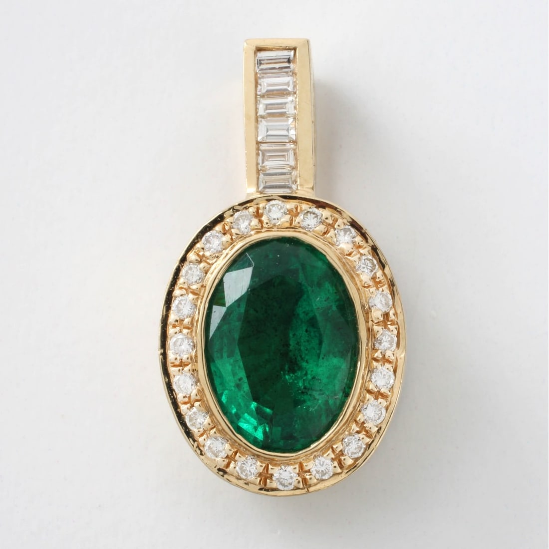 Emerald, Diamond and 14K Pendant: Fine Approx. 3.50 Carat Oval Cut Gen Quality Colombian Emerald and 14 Karat Yellow Gold Pendant Accented with Round Brilliant and Baguette Cut Diamonds. Emerald with vivid saturation of color. Stamped