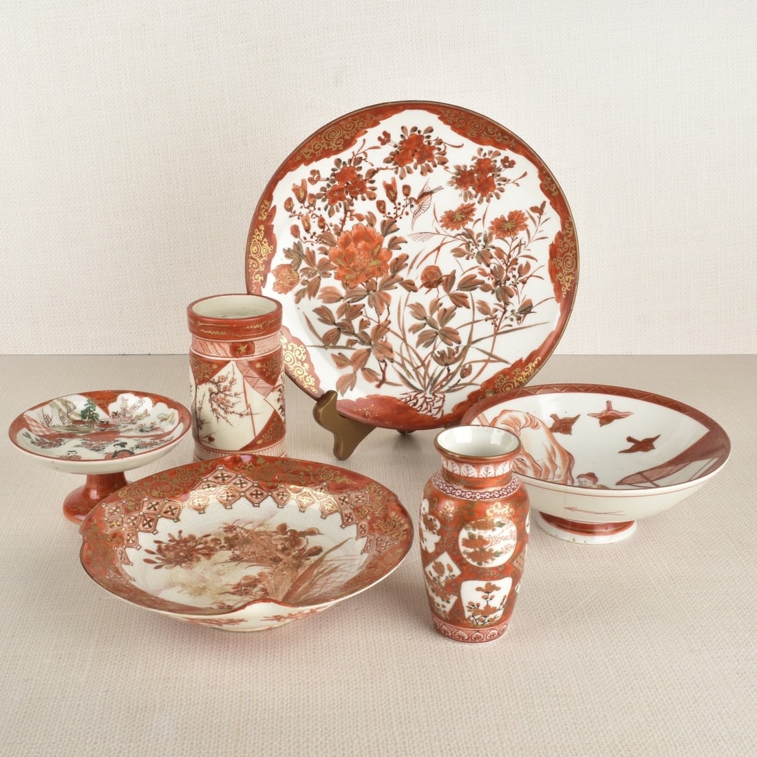 Japanese Kutani Ware Vessels: Six (6) Japanese Kutani ware red-orange-and-white-painted porcelain vessels, comprising three (3) footed bowls, one (1) dish, one (1) miniature vase, and one (1) cylindrical vessel, undersides with re
