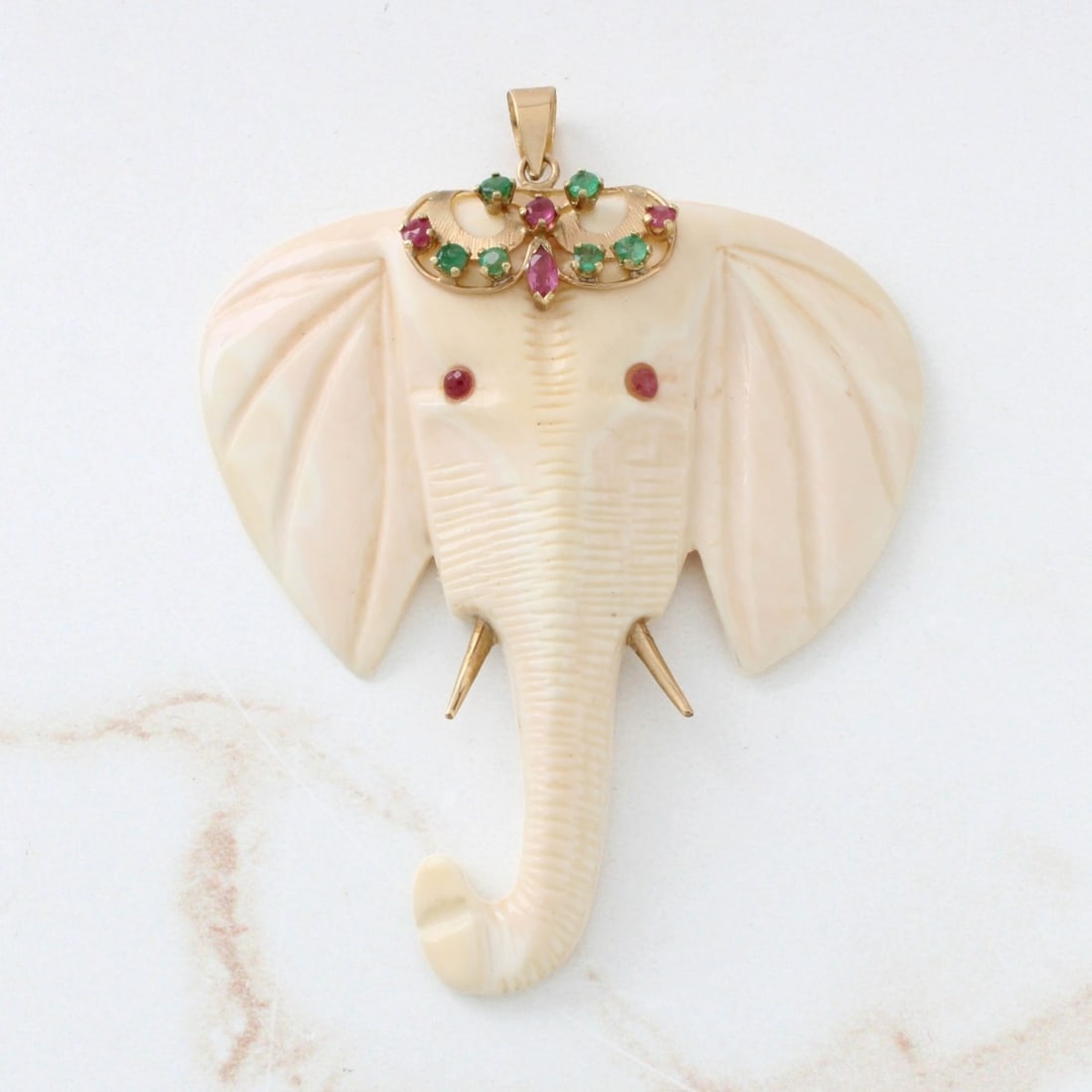 Gemstone and 14K Elephant Pendant: Vintage Carved Elephant Head Pendant Accented with Small Round Cut Emeralds and Rubies and 14 Karat Yellow Gold. Measures 2-3/8" L, 2" W. Approx. weight: 10.90 grams. We Will Not Ship This Item Outsid