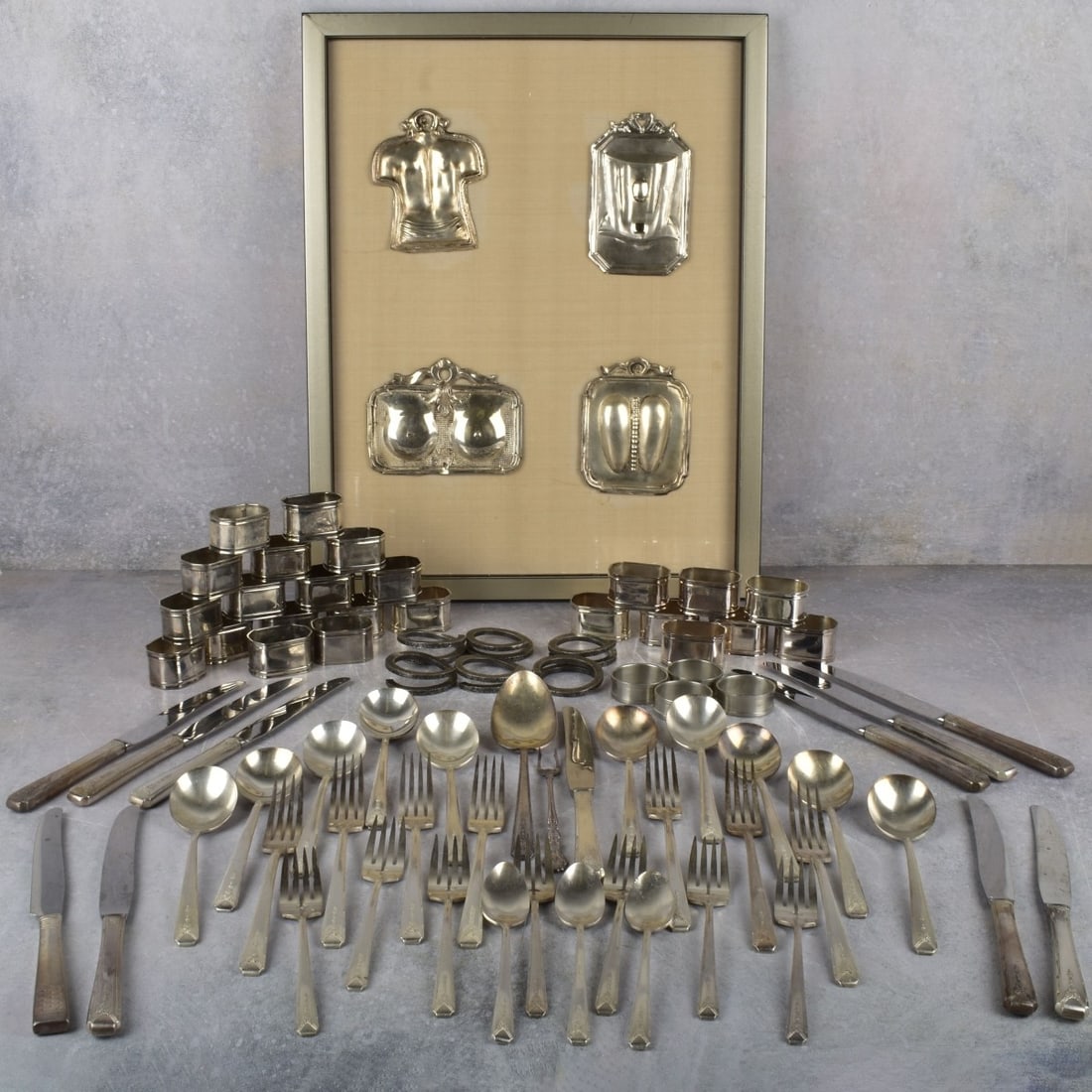 Ex-Voto Shields and Silver Plated Items: Ex-Voto Shields and Silver Plated Items. Including four (4) framed Ex-Voto shields, largest shield measures: 5" high, 3-1/2" wide, large collection of silver plate napkin rings, bag full of assorted s