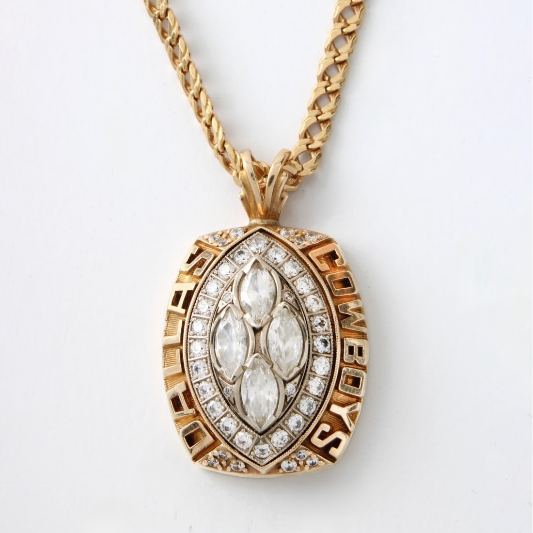 Super Bowl XXVIII Championship Pendant: 1993 Super Bowl XXVIII Championship Cubic Zirconia and 10 Karat Yellow Gold Pendant together with 14 Karat Yellow Gold Link Chain Necklace. These pendants were traditionally issued to players' wives,