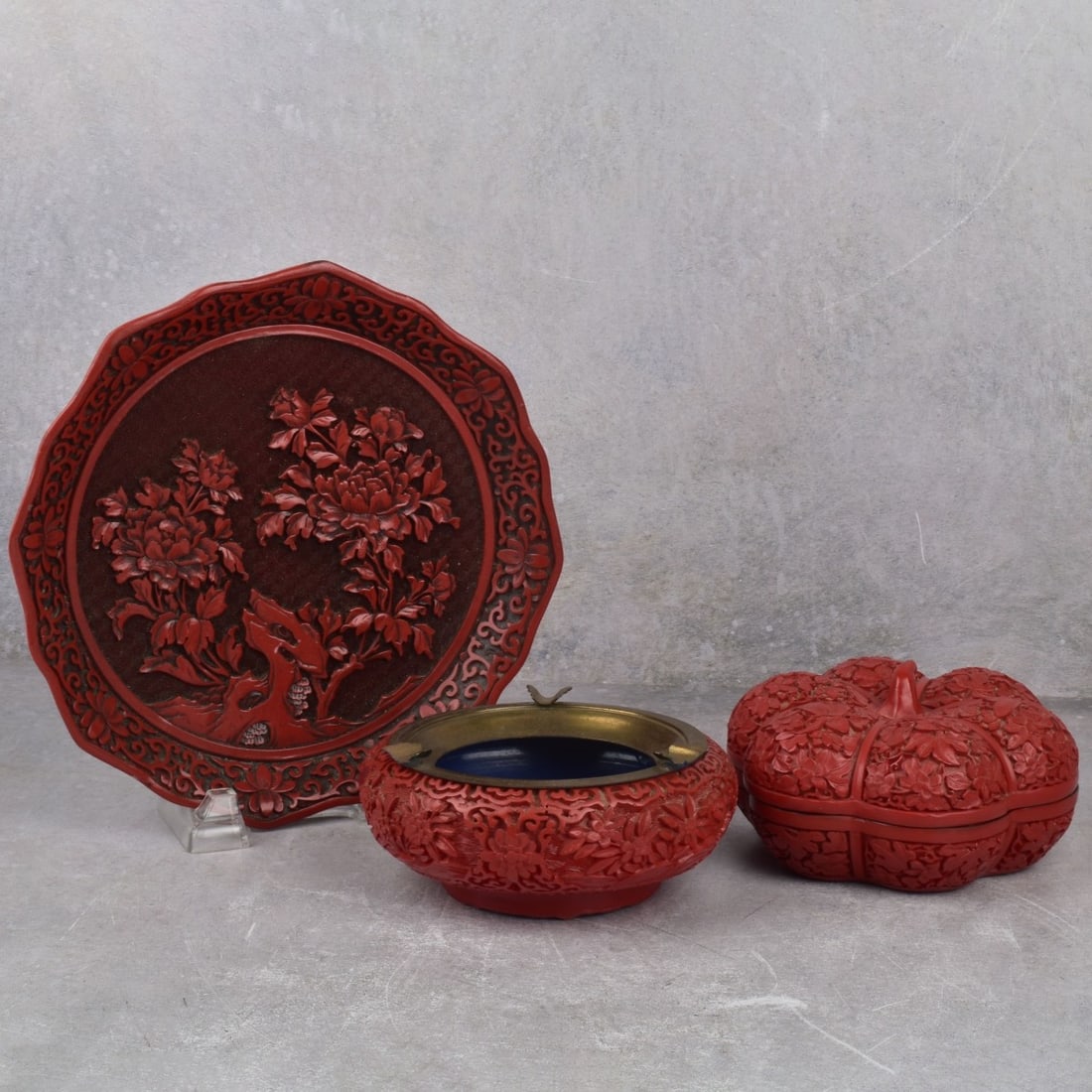 Chinese Resin Cinnabar Pieces: Three (3) Chinese Resin Cinnabar Pieces with Floral Motifs. Consisting of one (1) ashtray with brass top fitting and blue enamel interior. Measures: 2-1/2" H, 6" Dia., one (1) pumpkin shaped box. Meas