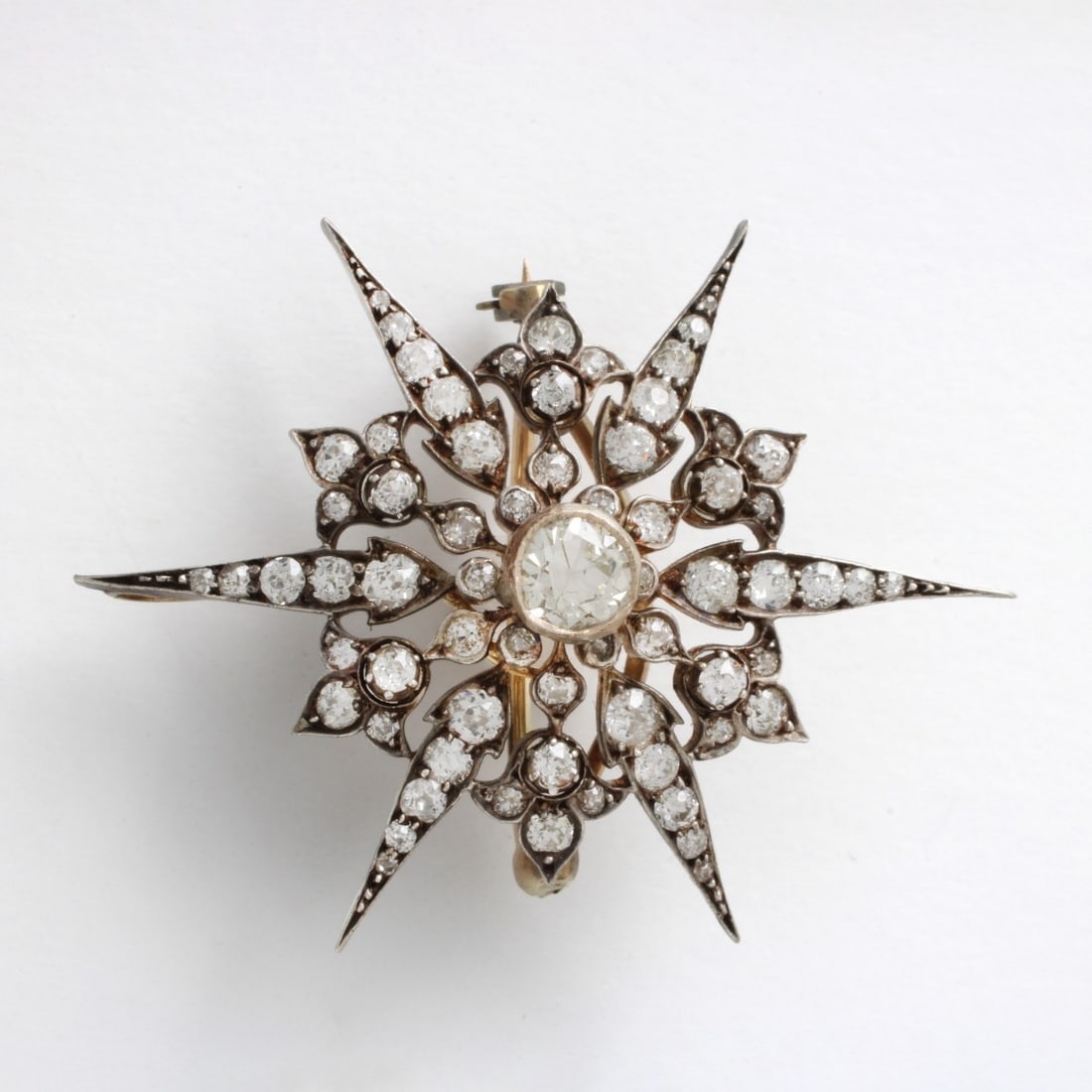 Diamond, Platinum and 18K Pendant: Antique Old European and Mine Cut Diamond, Platinum and 18 Karat Yellow Gold Starburst Pendant / Brooch. Diamonds H-I color, SI clarity. Measures 1-7/8" H, 1-1/2" W. Approx. weight: 9.01 grams. Kodner