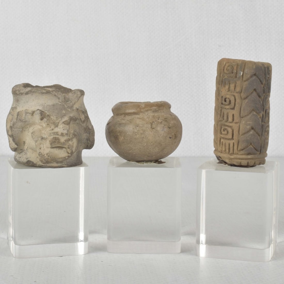 Pre-Columbian Mexican Pottery Items: Three (3) Pre-Columbian Mexican Pottery Items Mounted to Lucite Stands. One (1) jug measures: 1-3/4" high, 2" wide, 2-3/8" deep, stand measures: 2" high, 1-3/4" wide, 1-3/4" deep, one (1) pot measures