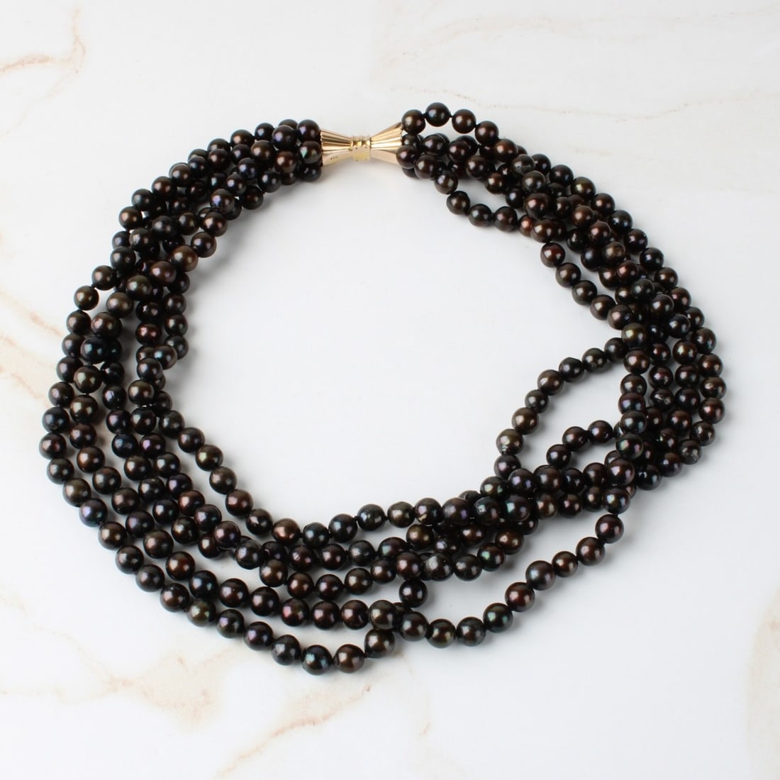 Black Pearl Necklace: Vintage Five Strand 5.5mm Black Pearl Necklace with 14 Karat Yellow Gold Clasp. Pearls with good luster and polish. Clasp stamped 14K. Measures 14-1/2" L. Approx. weight: 82.42 grams. Kodner