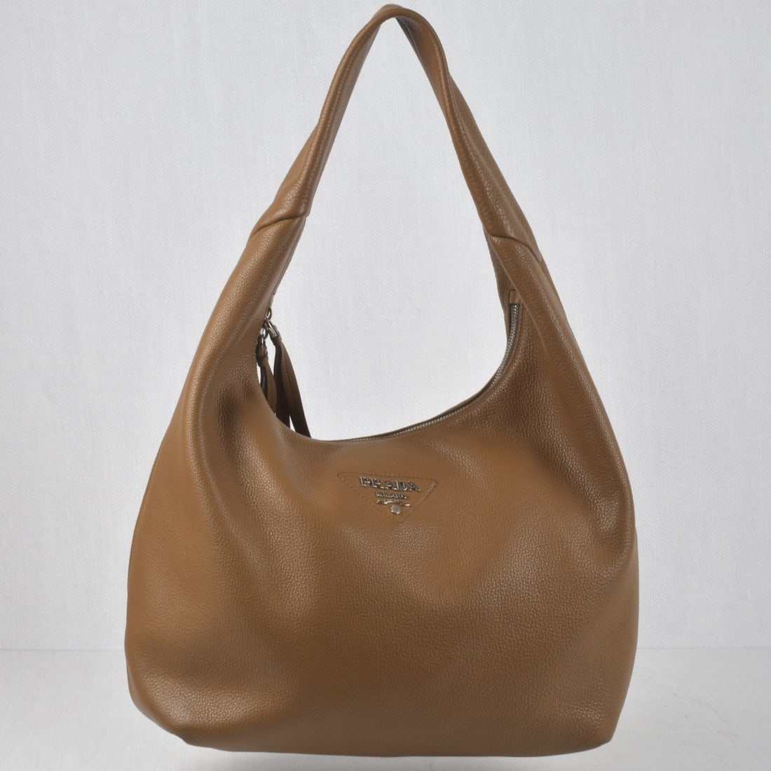 Prada Shoulder Bag: Prada Brown Pebble Hobo Shoulder Bag with Silver Tone Hardware. Measures: 10" high, 12" wide, 5-3/4" deep, drop measures:9". Kodner Galleries offers phone and absentee bidding at a low, flat 21%