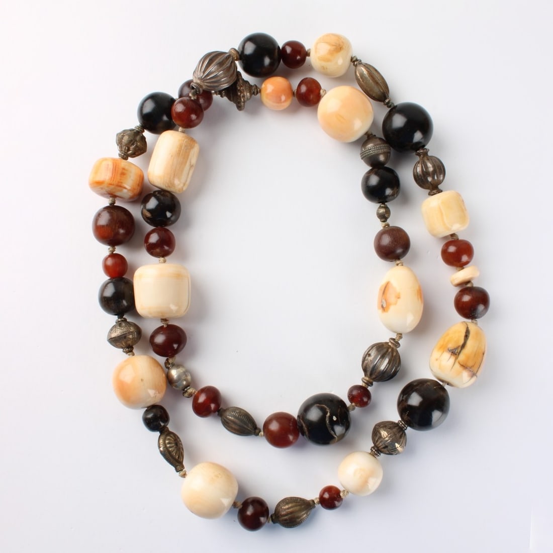 African Bead Necklace: Long and Large African Bead Necklace. Comprised of onyx, amber, agate, silver and carved organic material beads. Largest bead measure 24.5 mm. Necklace measures 38" L. Approx. total weight: 234.25